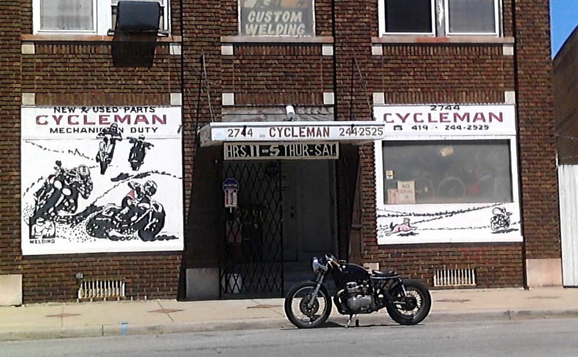 A bobber style motorcycle sits curbside in front of Cycle Man Motorcycle Shop on Lagrange Street in Toledo Ohio