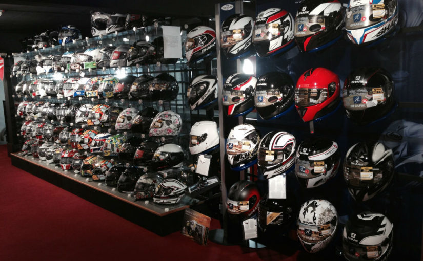 Approximately 80 Motorcycle Helmets on a display wall of a motorcycle dealership